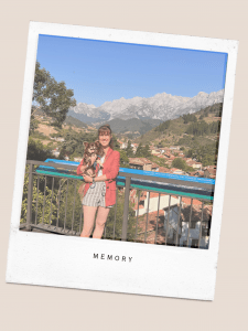 Owner standing on a viewing point holding her dog on her arms on top of Potes, Spain